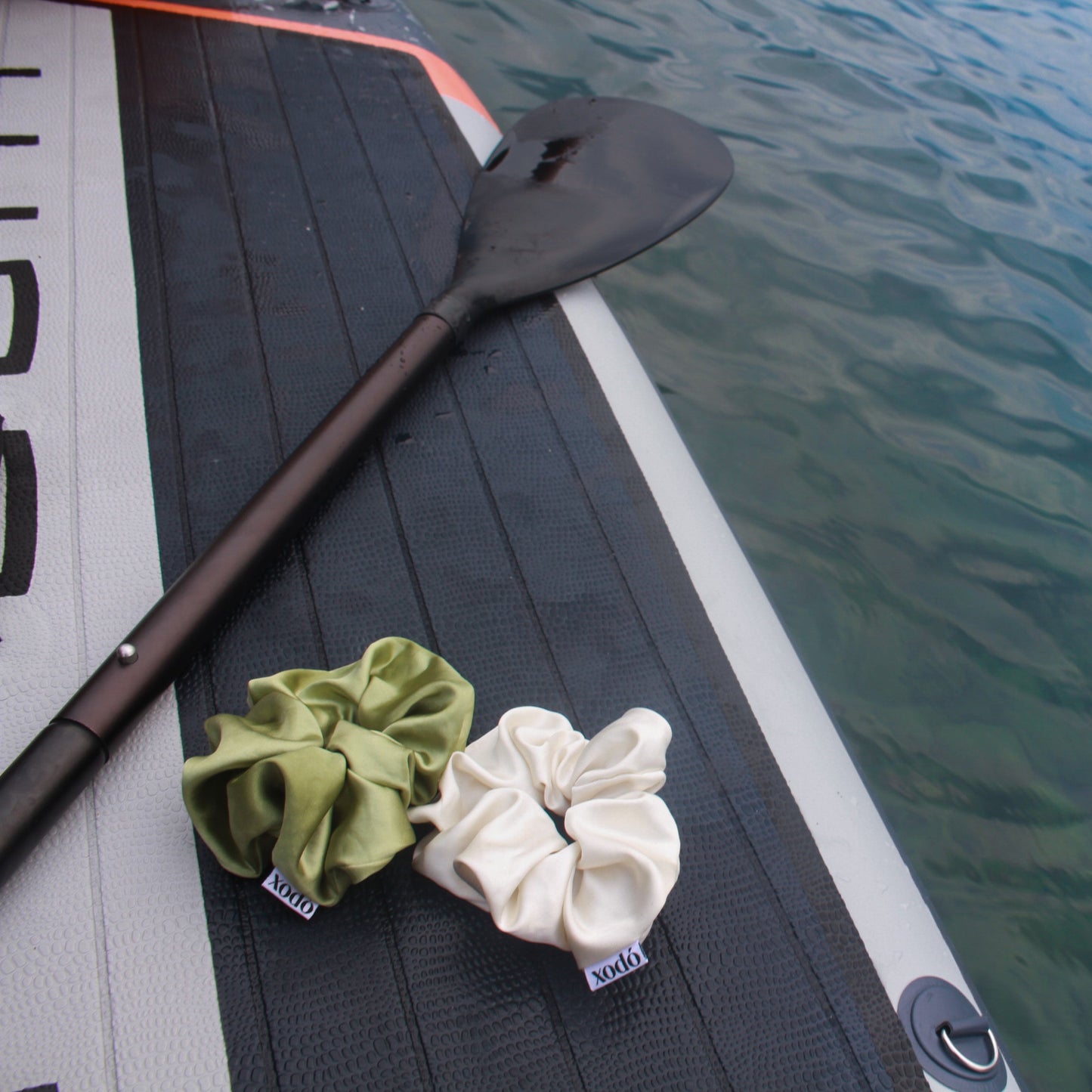 Two scrunchies on a paddle with water in the background